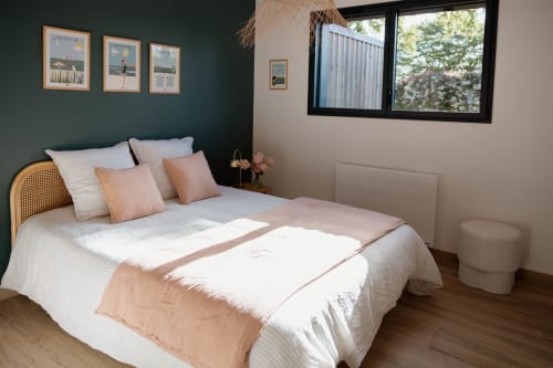 Bedroom at Manoir de la Nogrie cottage in Val d'Izé with rattan headboard, cream bedding, peach accents, dark teal wall art,