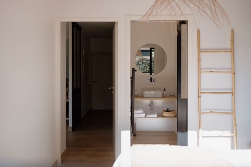 Modern bathroom in La Grange cottage at Manoir de la Nogrie with round mirror, vessel sink, and wooden ladder shelf