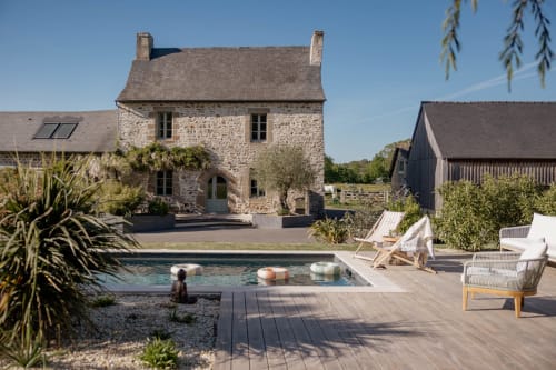 Manoir de la Nogrie cottage with pool, stone architecture, lounge chairs, and garden view in Val d'Izé