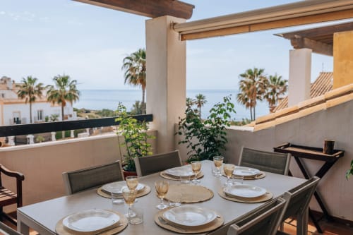 Stromboli triplex terrace at BH Marbella with sea view dining setup, palm trees, and Mediterranean coastal scenery
