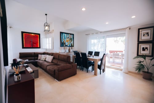 Modern living room at Stromboli triplex in Marbella with brown sectional sofa, dining area, and sea view balcony