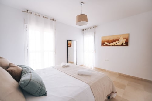 Bright modern bedroom at BH Marbella in Stromboli apartment with sea view, white walls, wooden floor, and contemporary