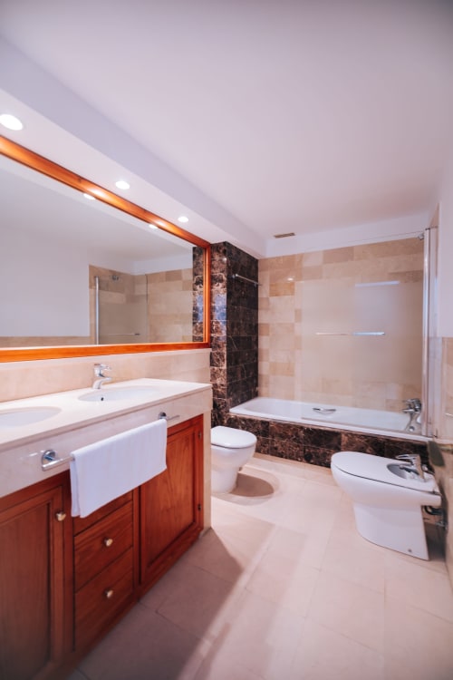 Modern luxury bathroom in Stromboli triplex apartment at BH Marbella with wooden vanity, marble accents, soaking tub and