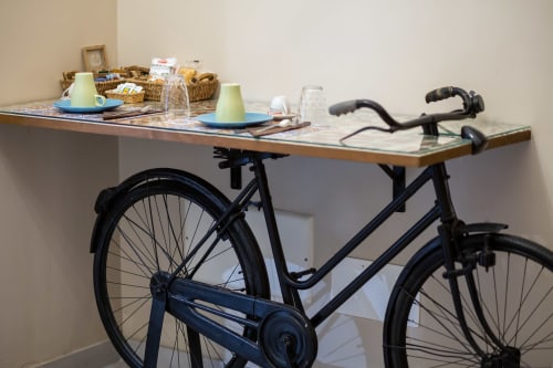 Black bicycle desk with green plates and wicker baskets in Casa Scola Loano's Manin room