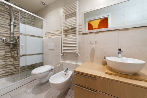 Modern bathroom in Casa Scola Loano's Manin room with white vessel sink, toilet, bidet, and rainfall shower