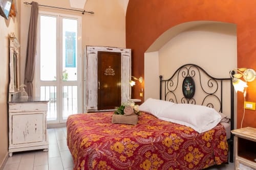 Camera Manin di Casa Scola Loano B&B in Italia con letto ornato, parete azzurro arancio e accesso al balcone