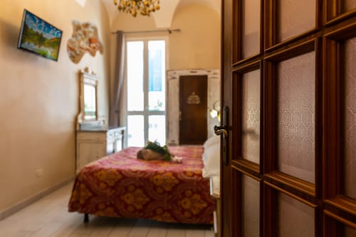 Manin room at Casa Scola Loano B&B in Italy, featuring bed with patterned bedcover, wooden wardrobe, and balcony access