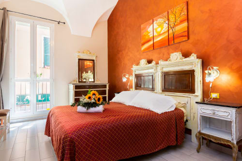 Camera Lina presso Casa Scola Loano BnB con pareti arancione vivaci, arredi color crema e biancheria terracotta a Loano, Italia