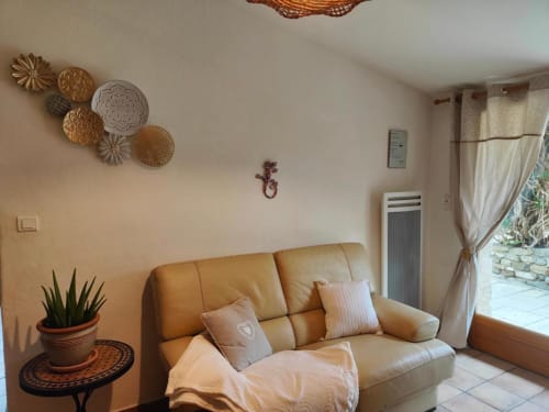 Séjour cosy au Domaine Bellavigne avec canapé en cuir tanné, assiettes décoratives et accès à la terrasse à Forcalquier