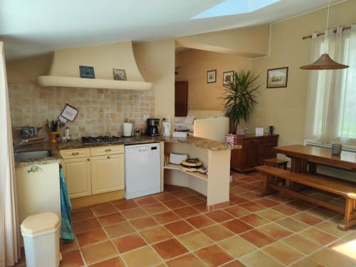 Cuisine ouverte spacieuse et salle à manger au Domaine Bellavigne avec carrelage en terre cuite, mobilier crème et bois rustique
