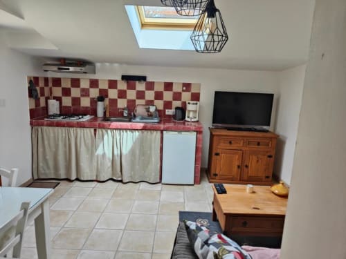 Kitchenette confortable avec dosseret à carreaux rouges, mobilier en bois et téléviseur aux Gîtes Domaine Bellavigne, Forcalquier
