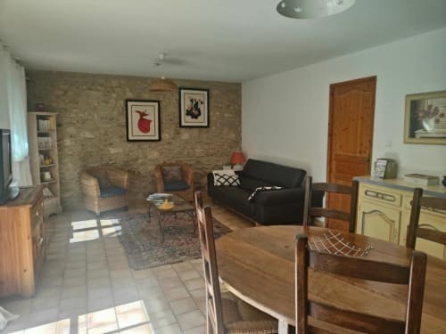 Spacieux séjour à Domaine Bellavigne Gîtes à Forcalquier avec mur en pierre, mobilier bois, canapé noir et salle à manger