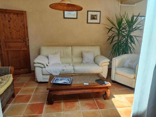 Canapé et fauteuil en cuir crème dans un séjour ensoleillé avec carrelage en terre cuite au Domaine Bellavigne, Forcalquier