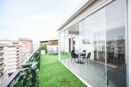 Terrazza dell'appartamento Cavour Deluxe a Bari con erba sintetica, arredi moderni e vista sullo skyline della città