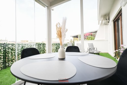 Moderna zona pranzo nell'Appartamento Deluxe Newhouse Cavour, Bari, con tavolo rotondo bianco, sedie nere e vista sulla città da