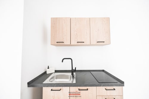Angolo cottura moderno nell'appartamento Newhouse Cavour Deluxe a Bari con mobili in legno chiaro, piano di lavoro scuro e acciaio inossidabile