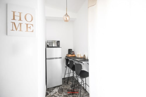 Angolo cottura moderno presso Newhouse Bari con frigorifero bianco, microonde, tavolo bar e decorazione HOME