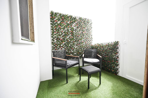 Terrazza privata di Newhouse Bari con lettini neri, parete verde artificiale e vista sulla città