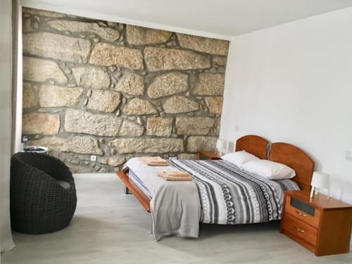 Modern bedroom at Campanhã Boutique Station in Porto with wooden bed, stone accent wall, and contemporary furnishings