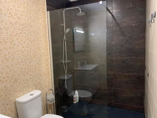 Modern bathroom at Campanhã Boutique Station with glass shower, toilet, and beige tile walls