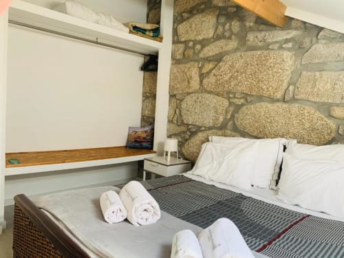 Modern bedroom at Campanhã Boutique Station Porto with rolled towels, stone accent wall, desk, and white bedding.