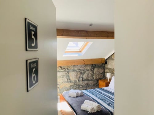 Campanhã Boutique Station room entrance with rolled towels on bed, stone walls, and skylight in Porto BnB