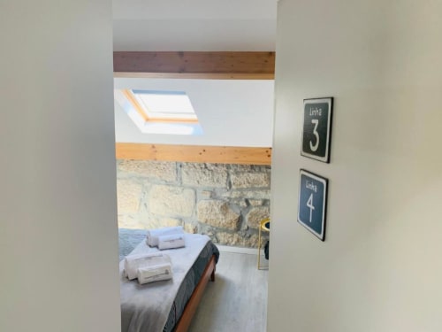 Bedroom doorway view at Campanhã Boutique Station in Porto showing bed with toiletries, stone wall, skylight, and room number