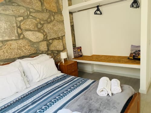 Cozy bedroom at Campanhã Boutique Station Porto with stone wall headboard, blue striped bedding, wooden desk, rolled towels,