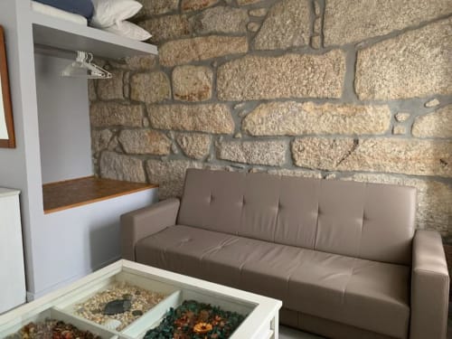 Quarto moderno na Estação Boutique Campanhã no Porto com sofá bege, parede de pedra e área de estar decorada