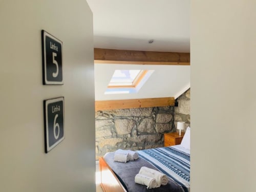 Linha 5 & 6 bedroom at Campanhã Boutique Station, Porto with stone wall, skylight, wooden beams, bed with white towels and