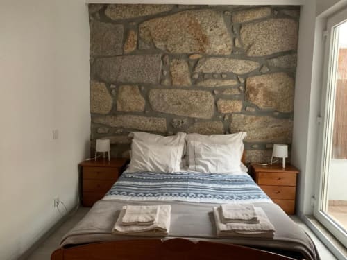 Bedroom at Campanhã Boutique Station in Porto with stone accent wall, wooden nightstands, white pillows, and access to patio