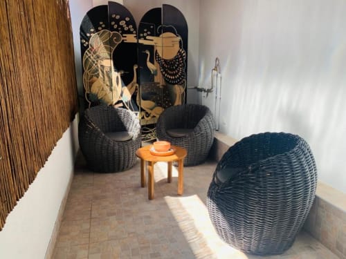 Cozy outdoor lounge area at Campanhã Boutique in Porto with woven pod chairs, decorative black screen, and wooden side table