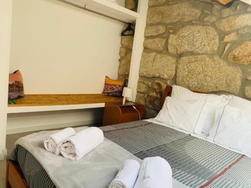 Cozy bedroom at Campanhã Boutique Station in Porto with stone walls, striped bedding, rolled towels, and wooden desk with