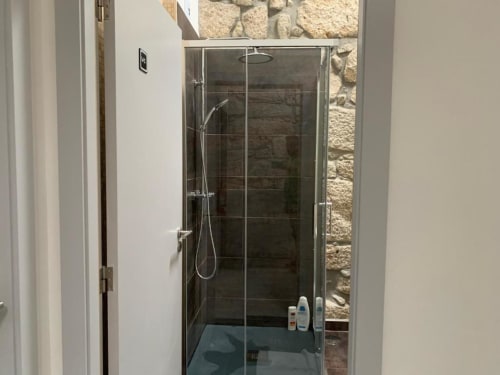 Modern glass shower enclosure at Campanhã Boutique Station hotel in Porto, Porto with dark tile walls and rainfall showerhead