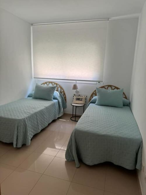 Twin bedroom in 3-bedroom Salou apartment with twin beds, wicker headboards, and garden views