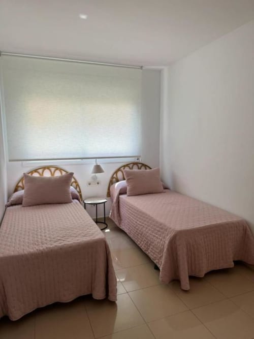Twin bedroom with rattan headboards, pink bedding, and garden view at Rentalaya apartment in Salou