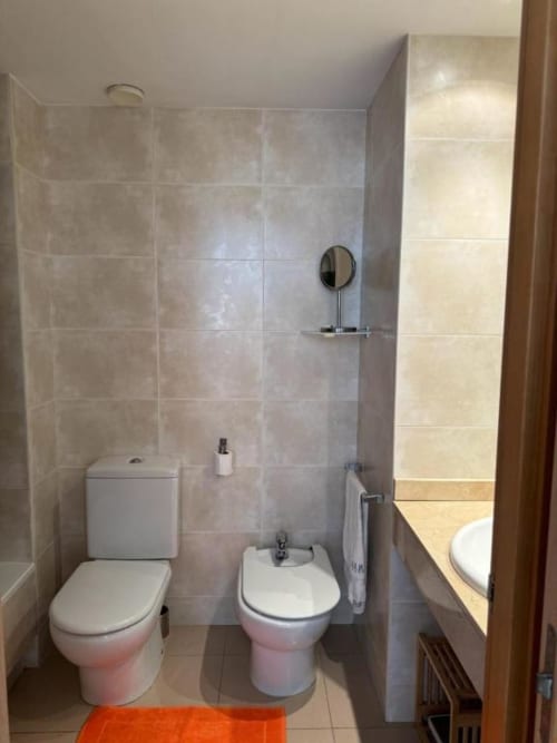 Modern bathroom in Salou apartment with two toilets, bidet, tiled walls, and shower enclosure