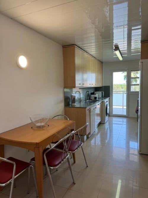 Modern kitchen and dining area in 3-bedroom Salou apartment with wooden table, stainless appliances, and garden views through