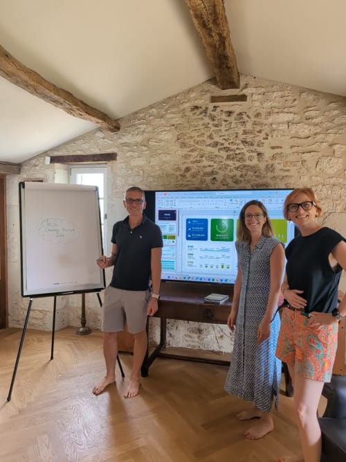 Four team members present business dashboard in stone-walled room at Old Presbytery Guest House, Saint-André-et-Appelles