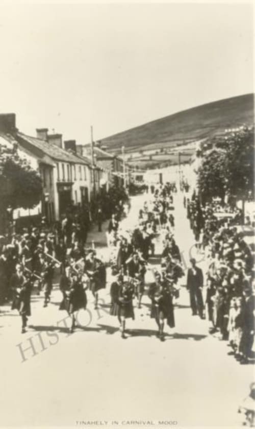 Historic street procession in Wicklow village with crowds, traditional buildings and rolling hills in background
