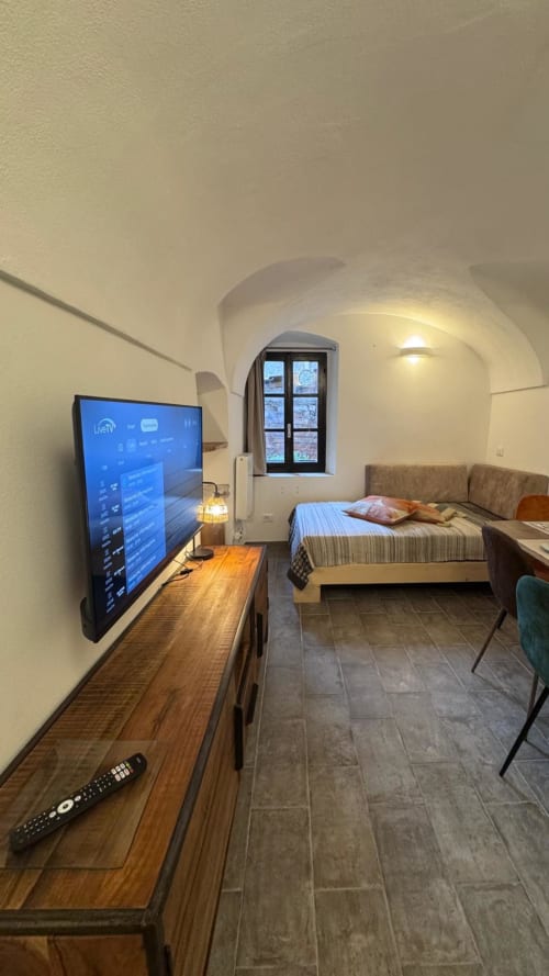 Moderno monolocale a Dolceacqua con TV, letto, scrivania e soffitto a volta con vista sulla città