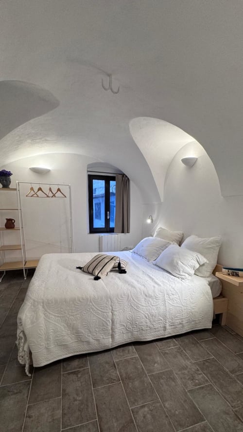 Camera da letto moderna bianca a Dolceacqua con pareti curve, vista sulla città e design minimalista