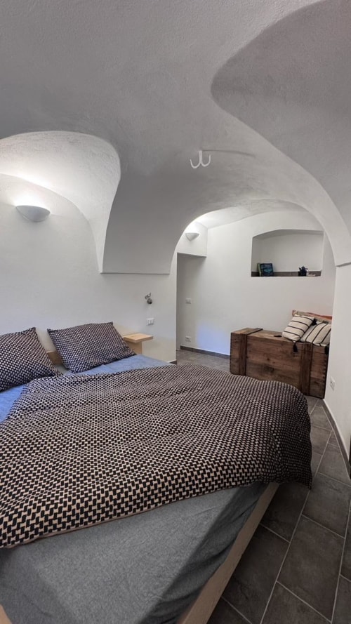 Camera da letto moderna con soffitti a volta bianchi, biancheria decorata, arredamento in legno e illuminazione incassata presso Talking Stones Group