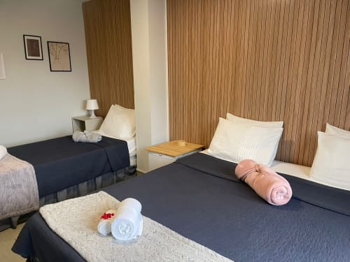 Chambre Twin à la Liber Guest House de Braga avec lits foncés, oreillers blancs et mur d'accent en bois
