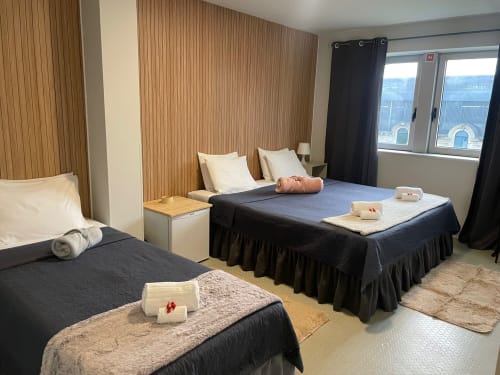 Spacieuse chambre d'hôtel à la Liber Guest House à Braga avec deux lits, boiseries et équipements modernes