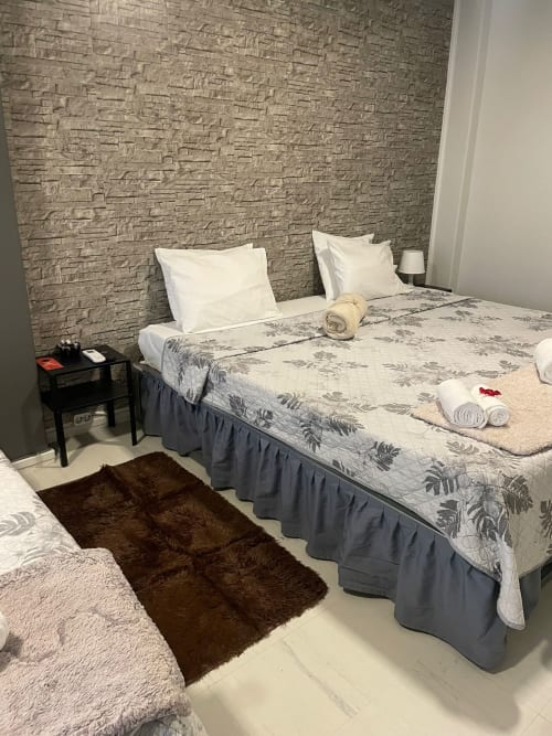 Chambre moderne à la Liber Guest House de Braga avec mur en pierre, oreillers blancs, literie fleurie et serviettes roulées