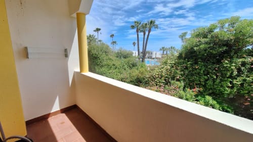 Varanda ensolarada com azulejos em terracota com vista para jardins exuberantes e piscina do Hotel Algarve Golden, Cabanas de Tavira