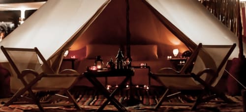 Tente glamping luxueuse avec assises confortables, éclairage chaleureux et foyer central au Lou Paradou Lodge à Grillon