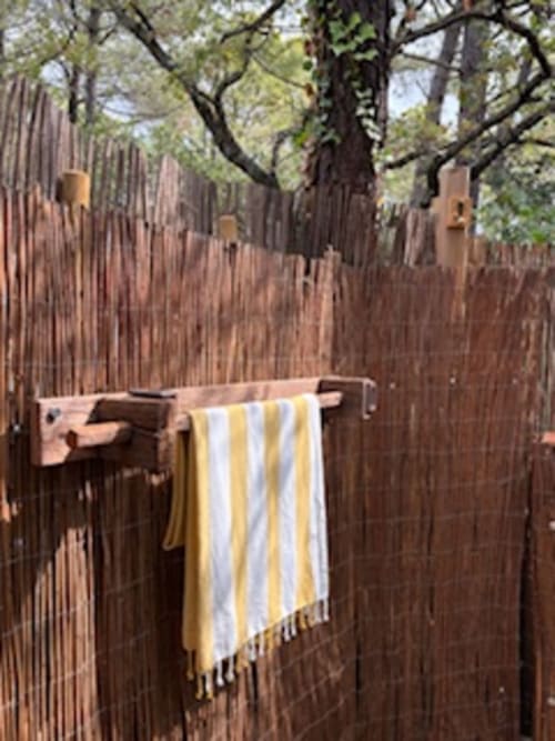 Serviette rayée jaune suspendue à un portant en bois avec vue sur le jardin au Lou Paradou Lodge, Grillon