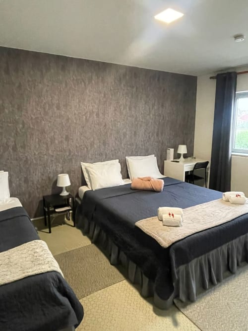 Chambre triple économique à la Liber Guest House Braga avec deux lits, bureau et salle de bain commune